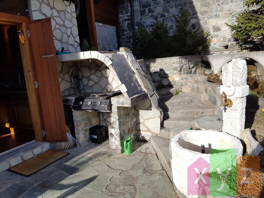 Le coin grill de la terrasse en pierre naturelle avec la fontaine et accès à la cuisine